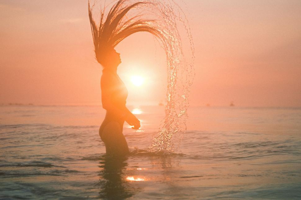 Free Image of Sunset silhouette with water splash creating a perfect arc 