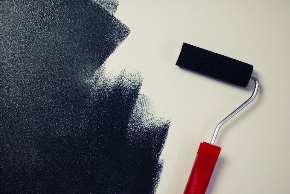 Free Image of Close-up view of a paint roller with black paint creating texture wall. 