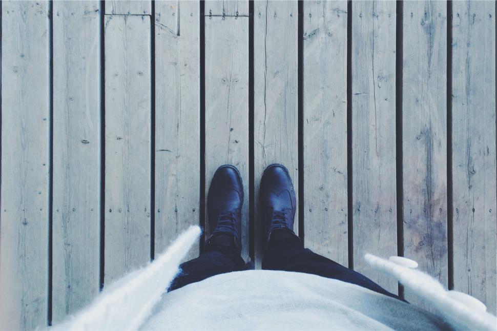 Free Image of Person standing on wooden deck looking down at their feet 