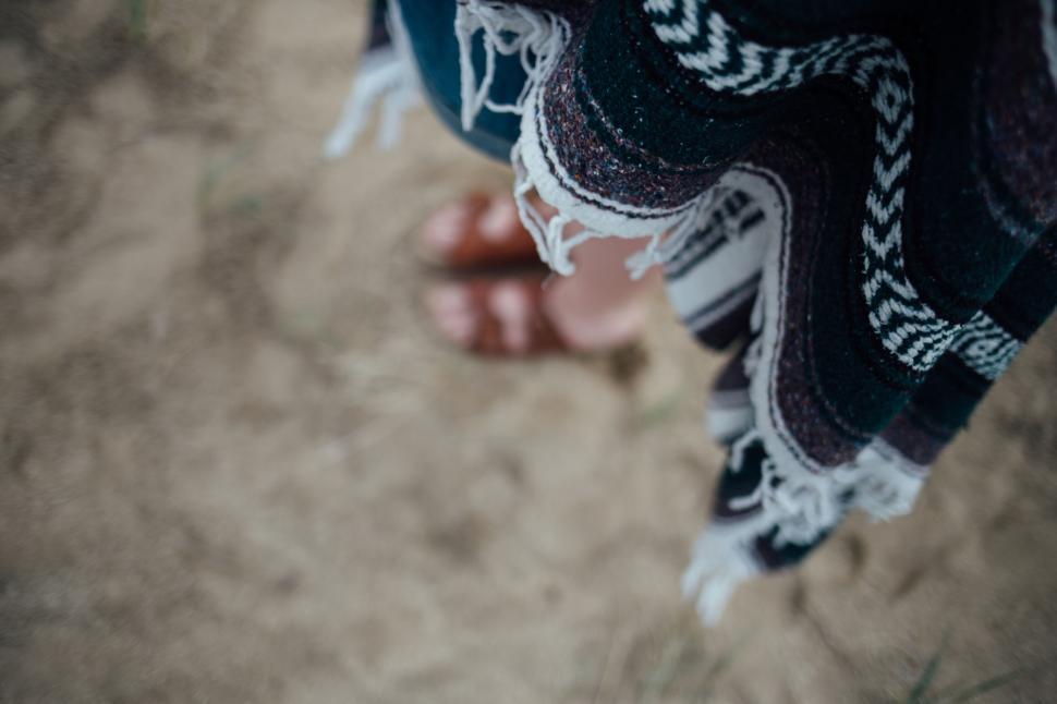 Free Image of Person wrapped in a blanket standing on sandy ground outdoors 