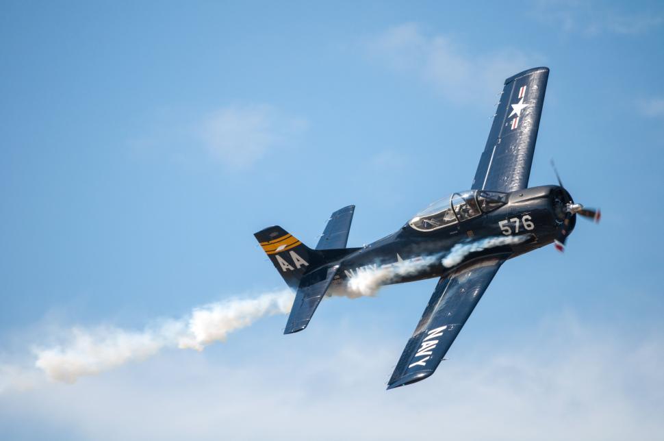 Free Image of Airplane making a smoke trail against a clear blue sky backdrop. 
