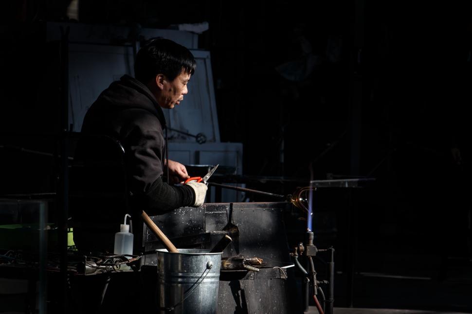 Free Image of Individual with welding equipment in dimly lit workspace at night 
