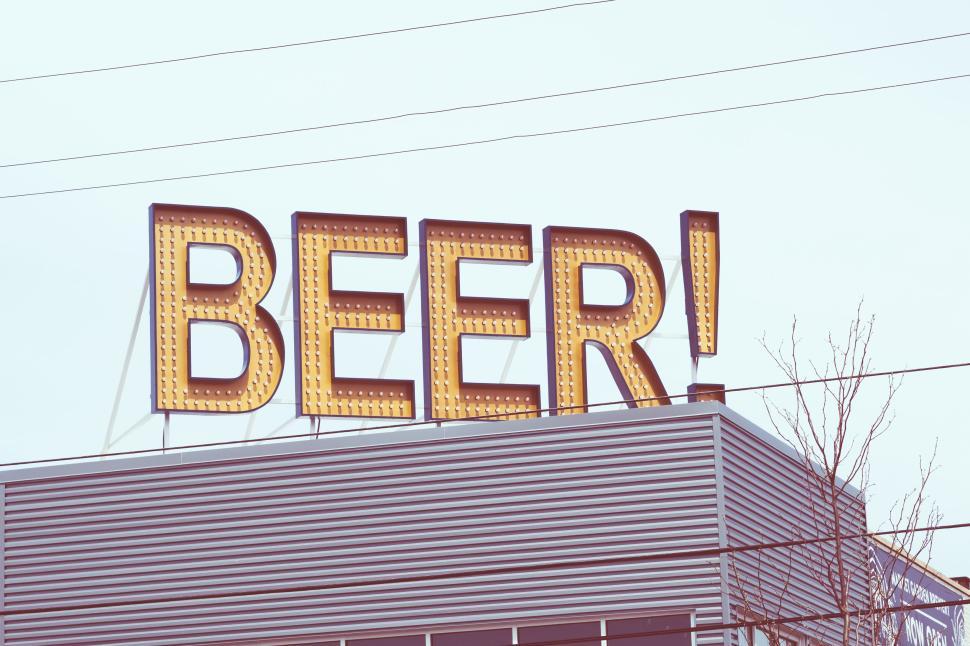 Free Image of Bright sign reading  BEER!  atop a modern metallic building facade. 