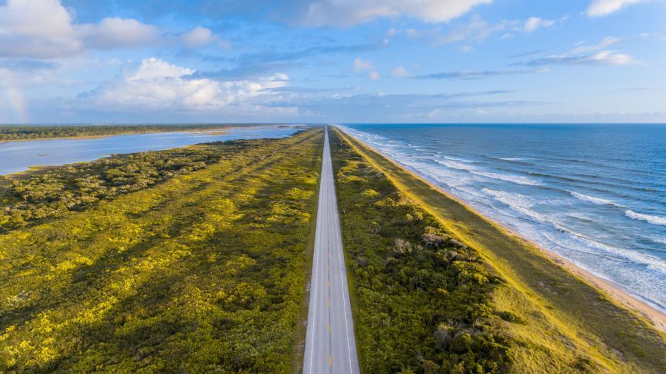 Free Image of Aerial view of endless road along coastline with ocean and greenery. 