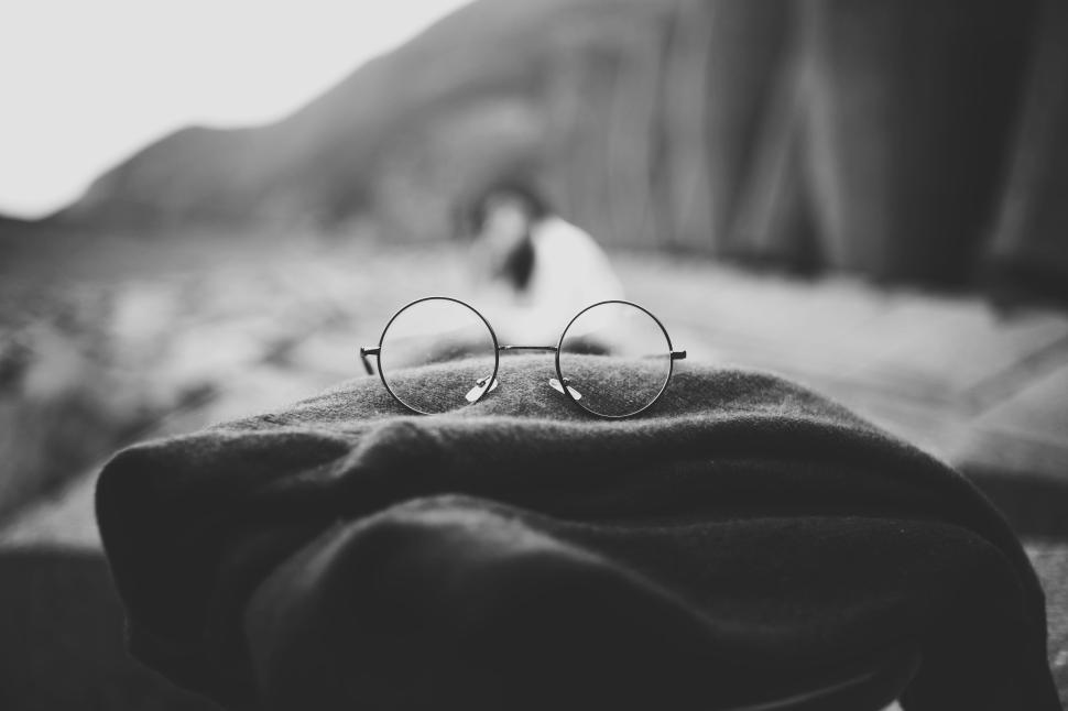 Free Image of Focus on round glasses with a blurred figure in the background 