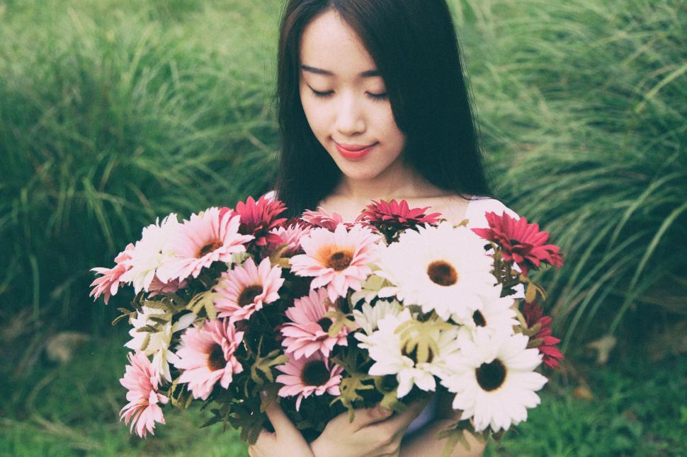 Free Image of Woman holding a bouquet of colorful flowers in a grassy field 