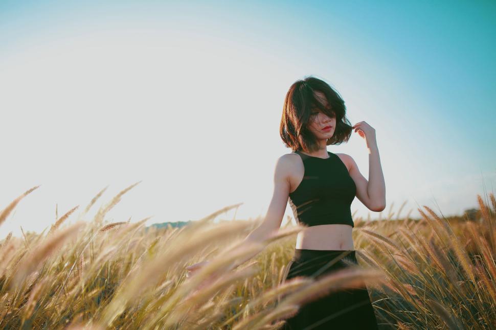 Free Image of Woman in Black Workout Attire Standing in Field with Tall Grass 