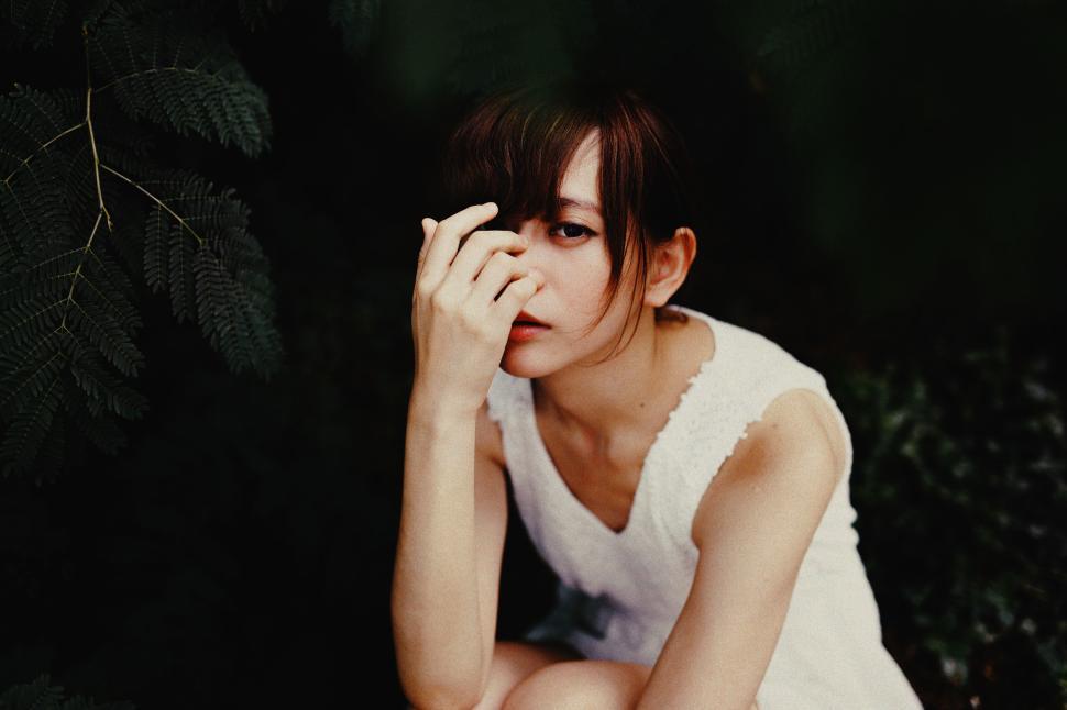 Free Image of Person in White Dress Sitting in a Lush Green Garden Setting 