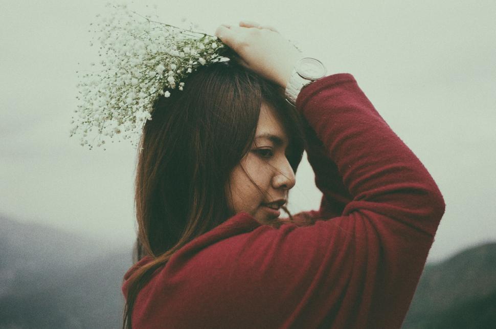 Free Image of Young woman wearing red coat with flowers on head 