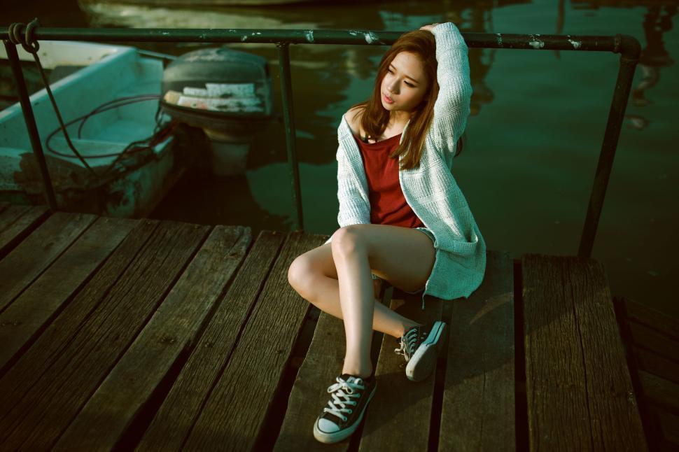 Free Image of Woman sitting on a dock by the water during golden hour 