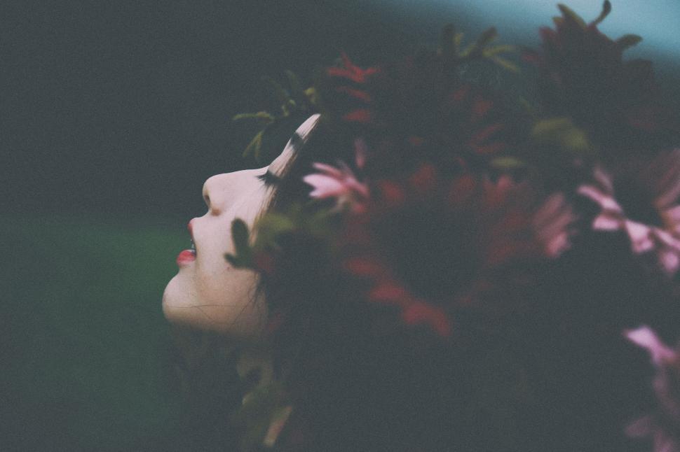 Free Image of Artistic portrait partially obscured by flowers in low-light setting 