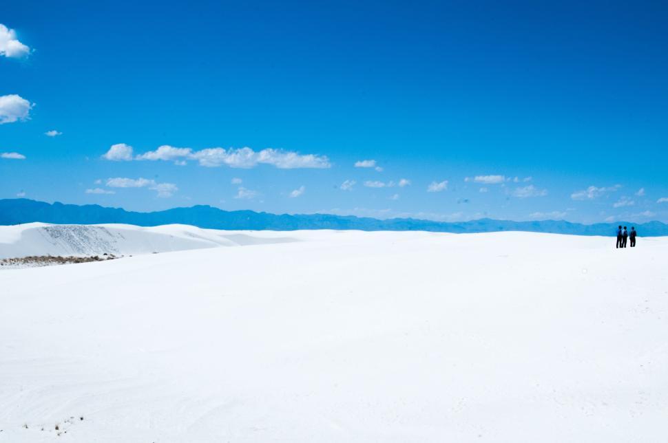 Free Image of Expansive white sandy desert under a bright blue sky with mountains 