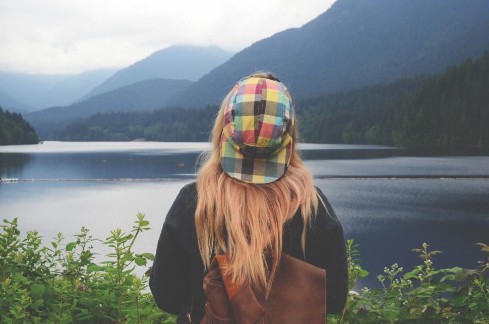 Free Image of Person with a colorful hat overlooking a serene mountain lake 
