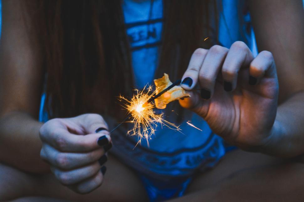 Free Image of Person holding sparklers with hands visible in the dark setting. 