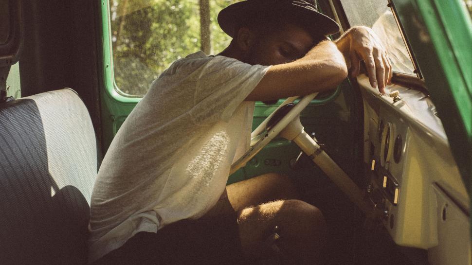 Free Image of Man fixing an old truck cabin leaning over steering wheel inside. 