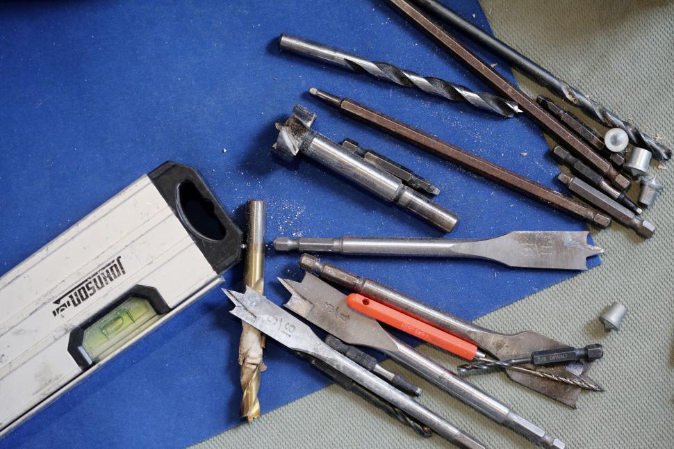 Free Image of A collection of various drill bits over a blue surface 