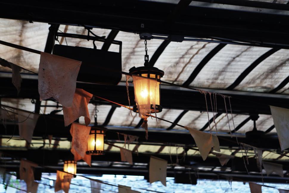 Free Image of Illuminated hanging lantern and bunting in rustic indoor setting 
