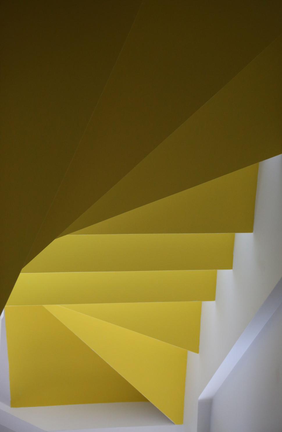 Free Image of Yellow spiral staircase with sharp angular geometric elements and light. 