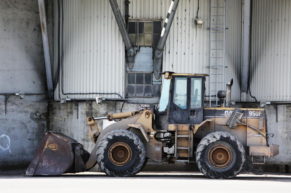 Free Image of Bulldozer parked indoors under structured industrial building pipes 
