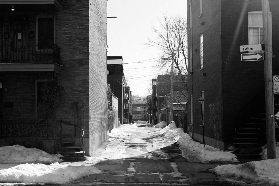 Free Image of Narrow street between brick buildings with snow covering the ground. 