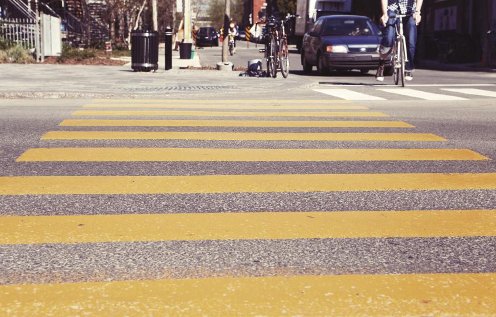 Free Image of Yellow striped zebra crossing on a busy urban street during daytime. 