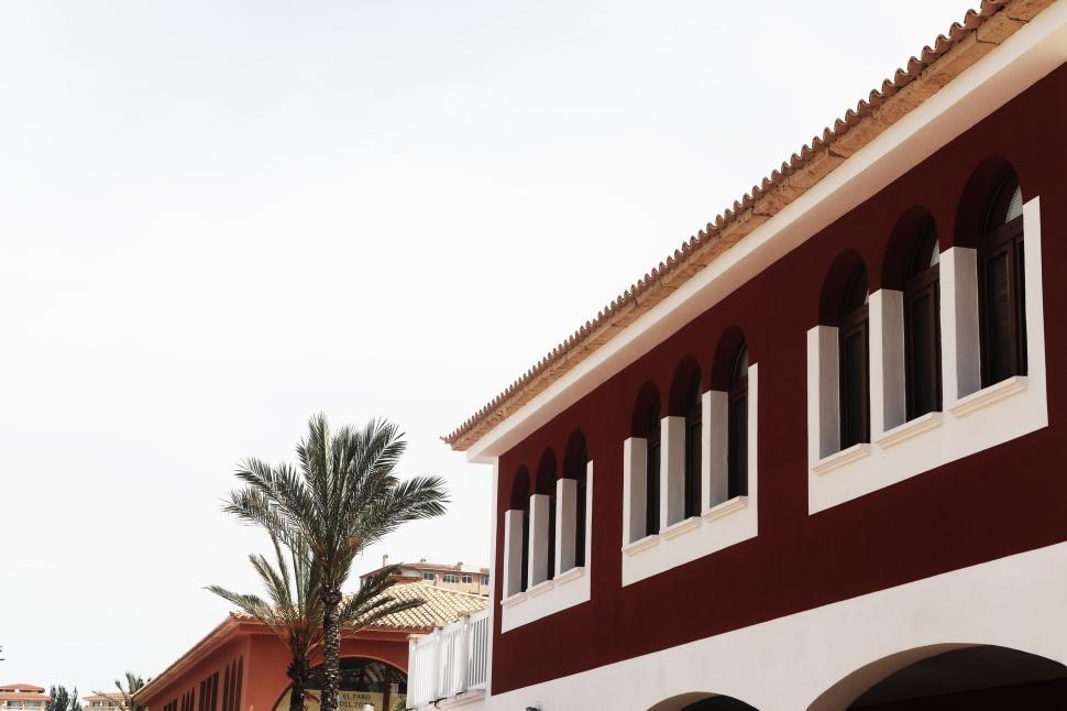Free Image of Mediterranean-style buildings with palm trees on a sunny day. 