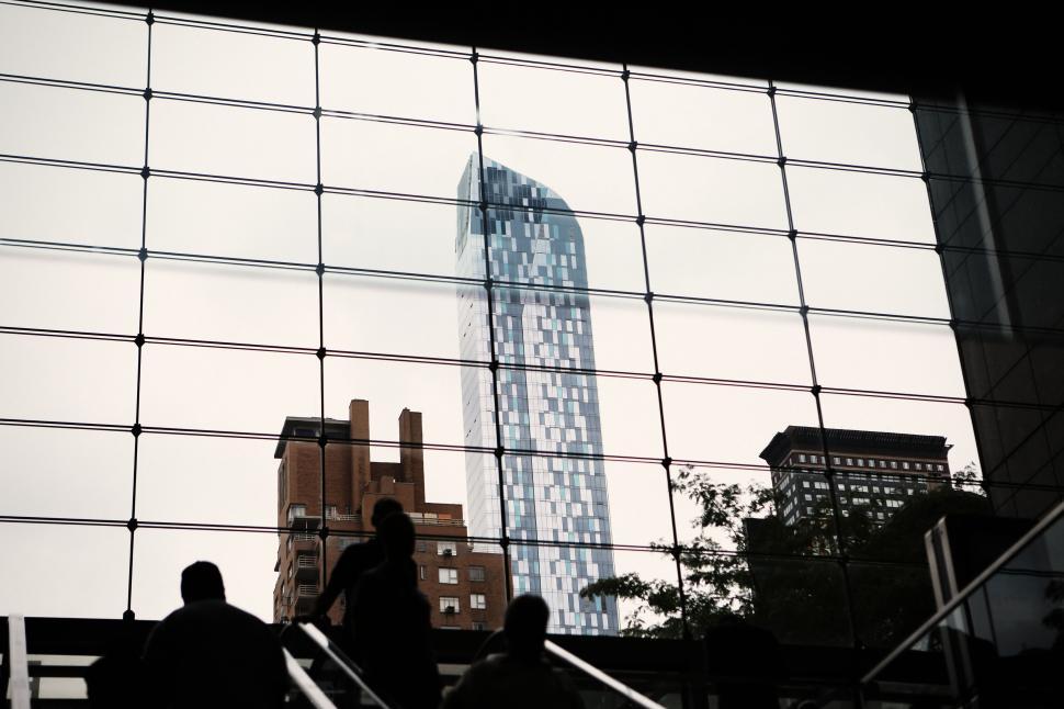 Free Image of View of modern skyscraper through glass window on a cloudy day. 