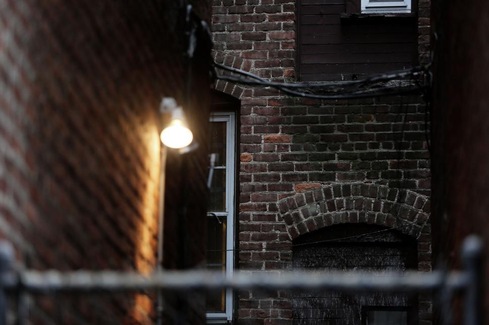 Free Image of Dimly lit narrow alleyway between old brick buildings at dusk 