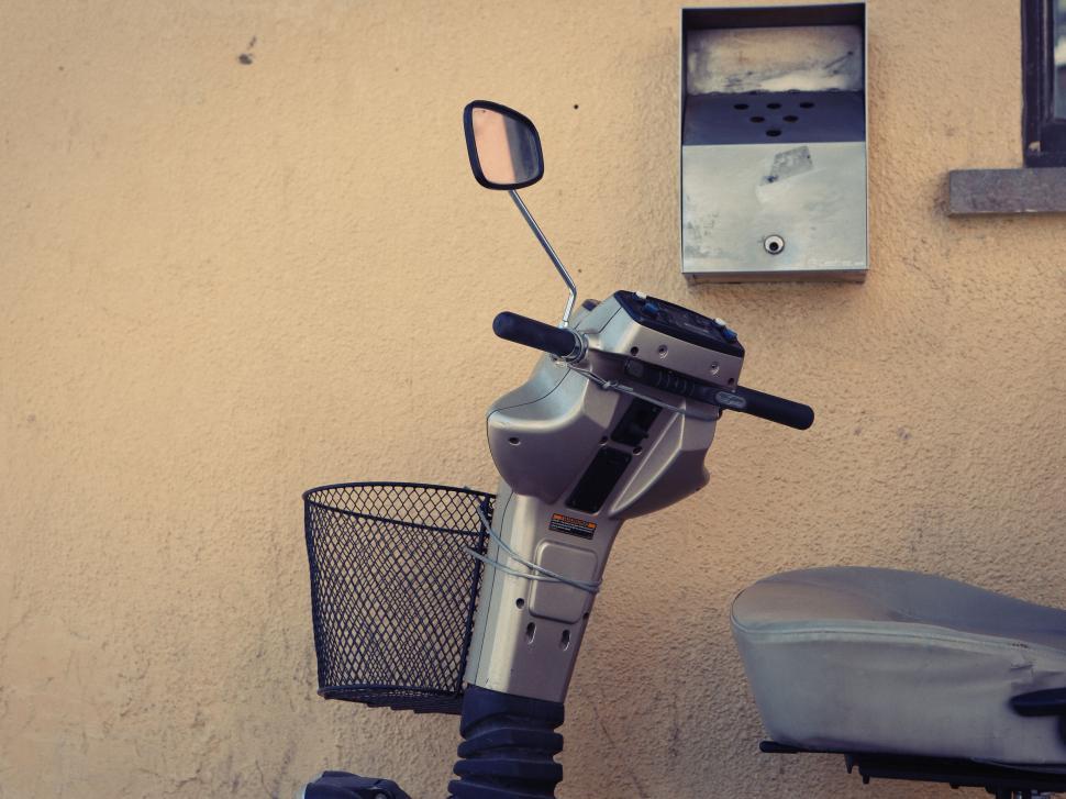 Free Image of Modern scooter parked by a wall with mailbox and mirror visible 