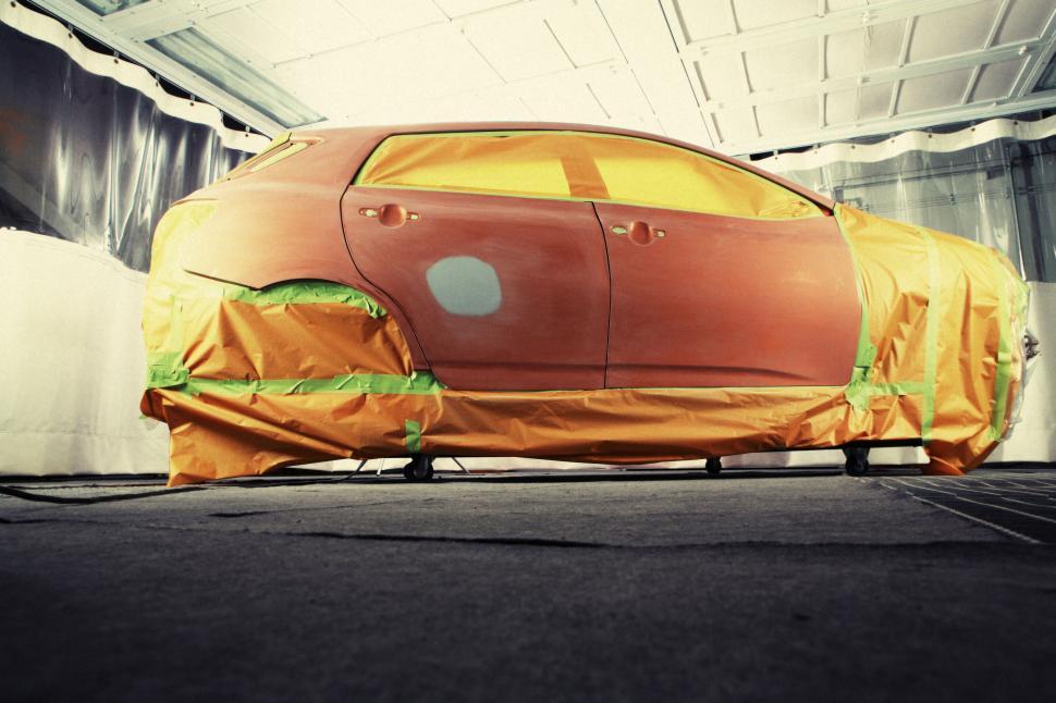 Free Image of Car undergoing a painting process in a protective, clean environment. 