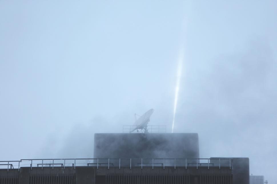 Free Image of Satellite dish on building rooftop captured through misty atmosphere 