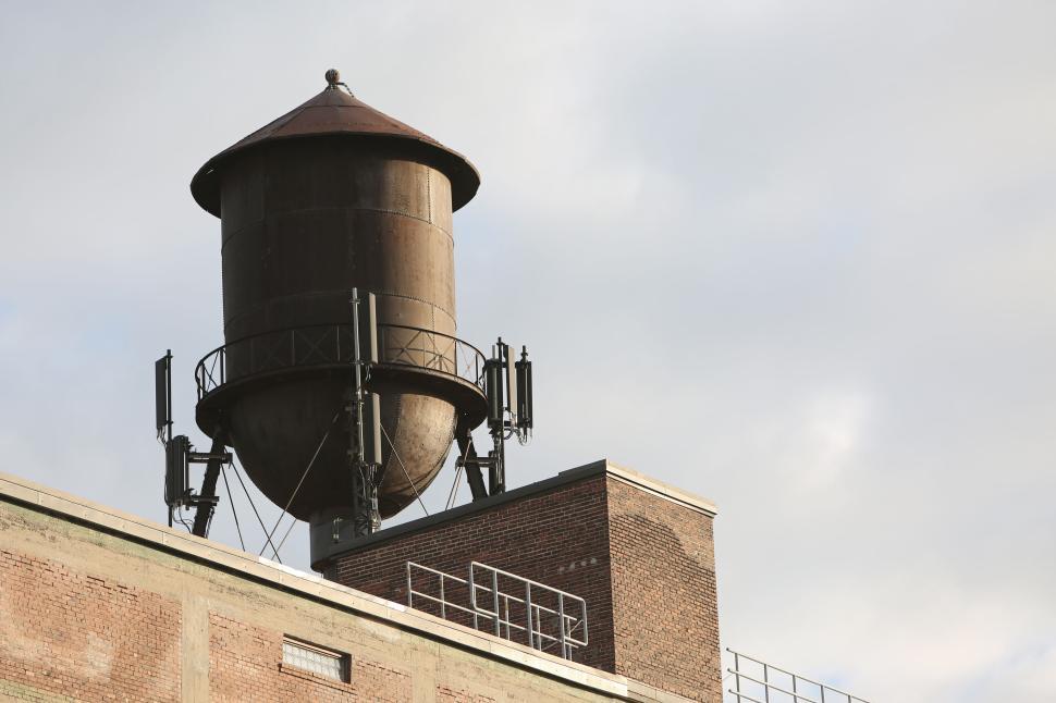Free Image of Large rusted water tower on top of an industrial building rooftop 