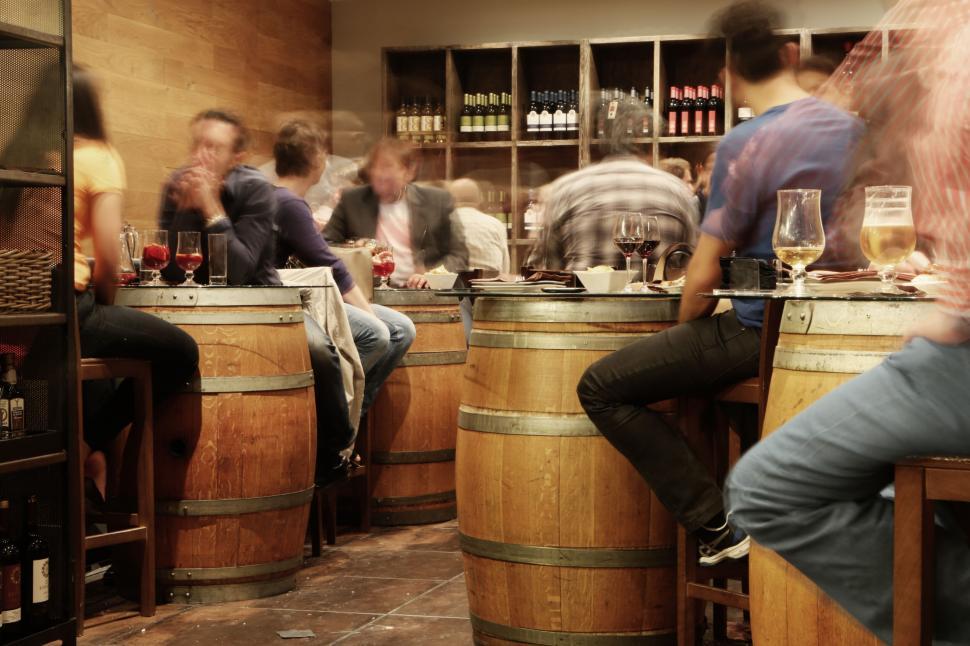 Free Image of People socializing over drinks inside cozy bar with barrel seats. 