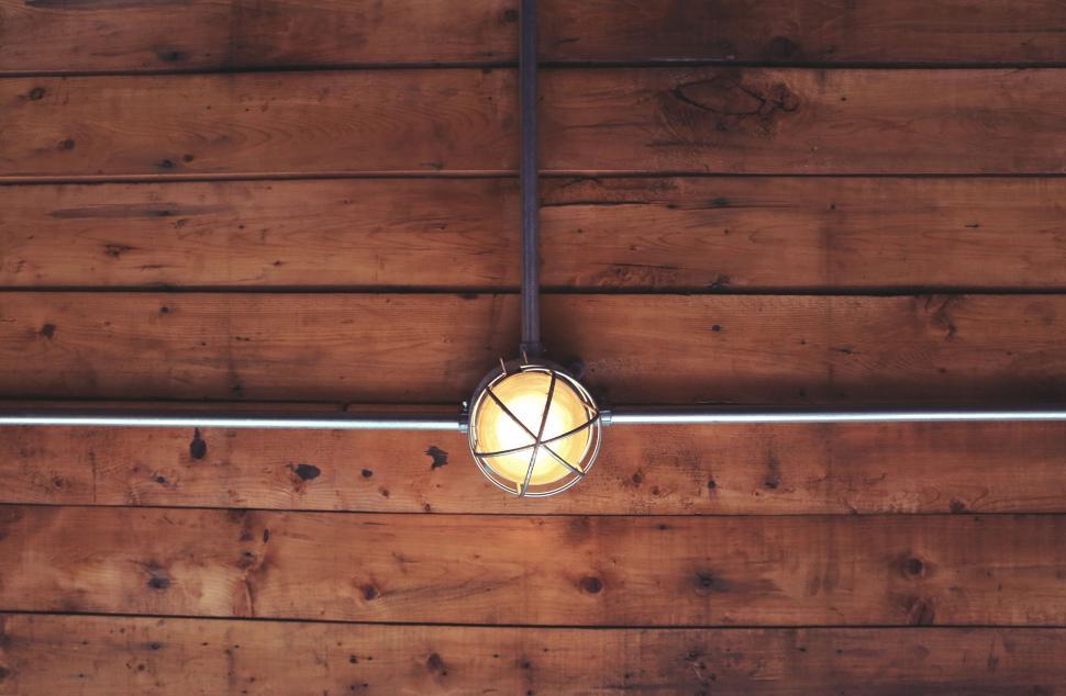 Free Image of Wooden ceiling with a metal cage light fixture, warm and cozy feel. 