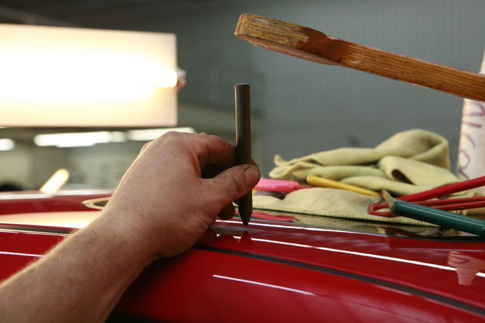 Free Image of Hand working on car body with tools, showcasing automotive repair process. 