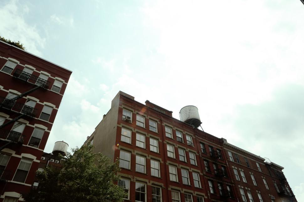 Free Image of Urban buildings with water towers under a partially cloudy sky 