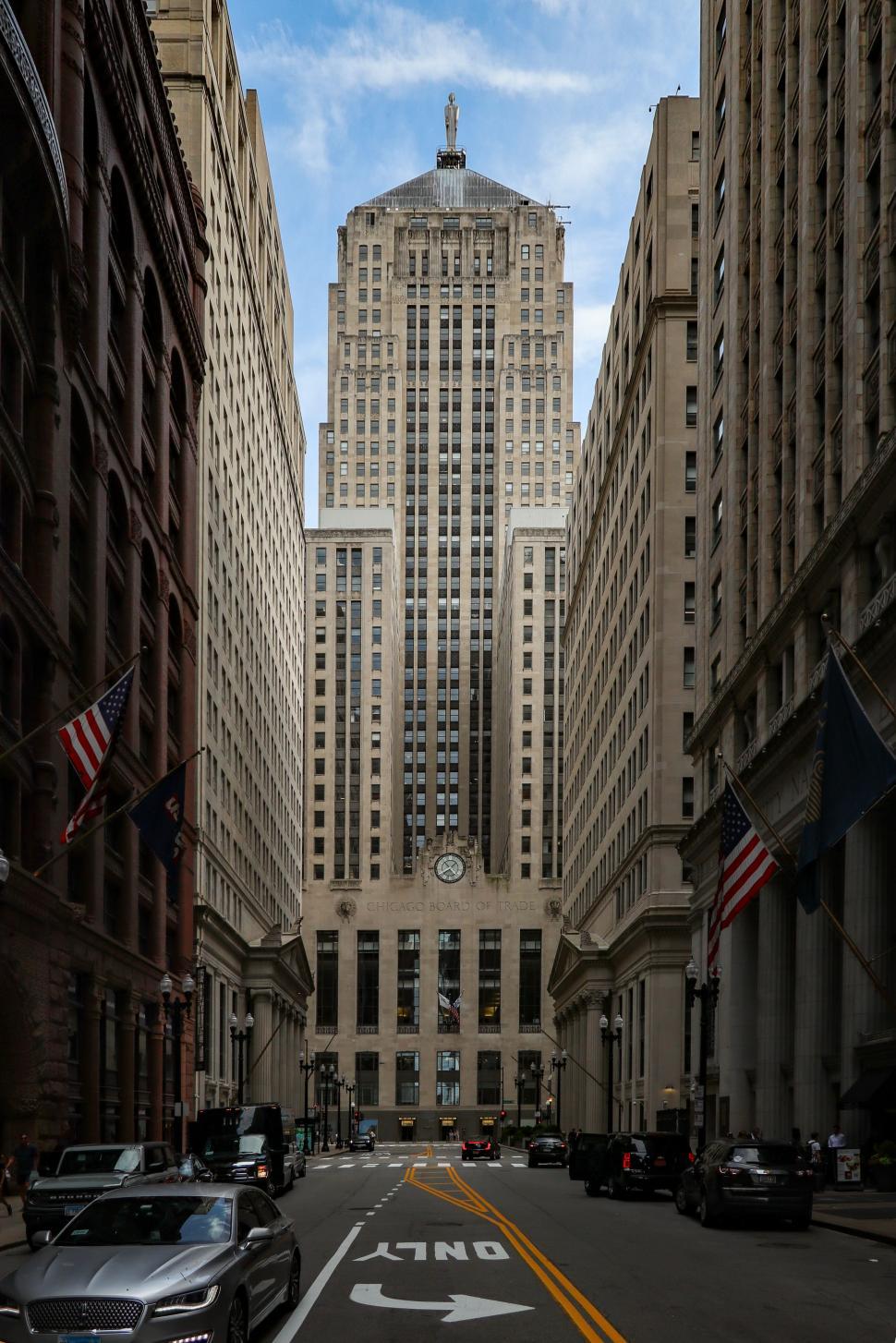 Free Image of Tall Chicago Board of Trade skyscraper framed by buildings on a narrow city street 