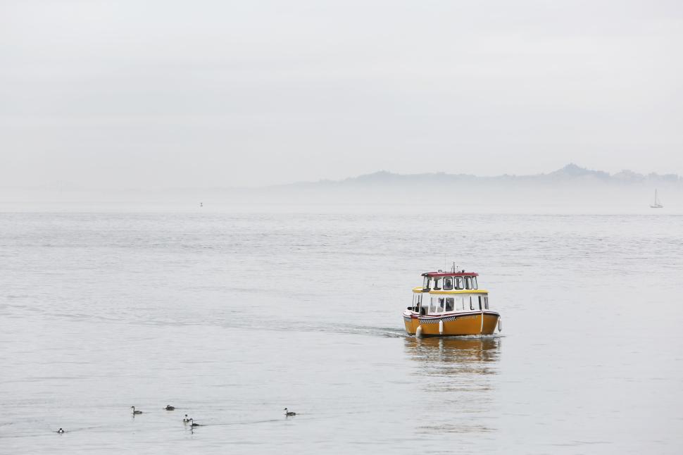 Free Image of Yellow boat navigating through calm waters on a misty day. 