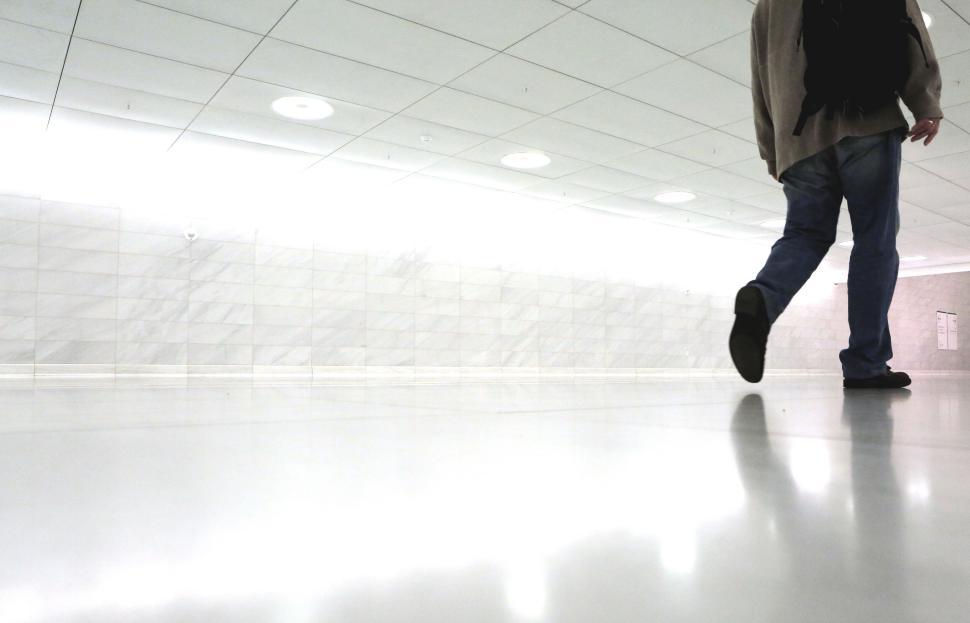 Free Image of Person walking through clean modern corridor with reflective floor 