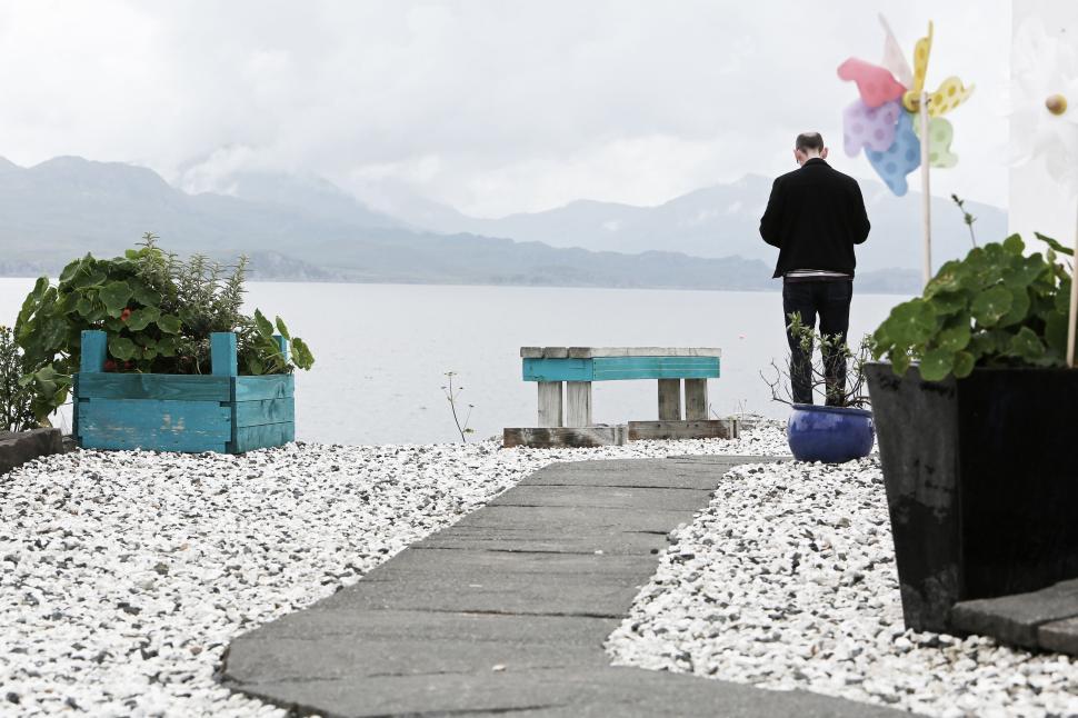 Free Image of Person standing near water at a rocky garden with colorful decor. 