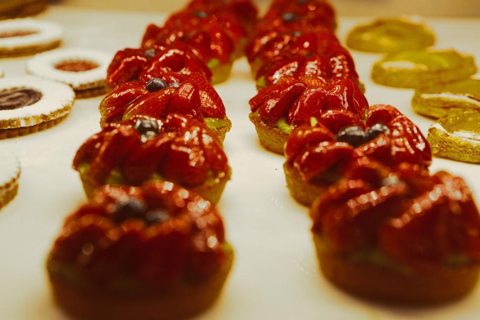 Free Image of Array of colorful pastries with red toppings displayed in a bakery 