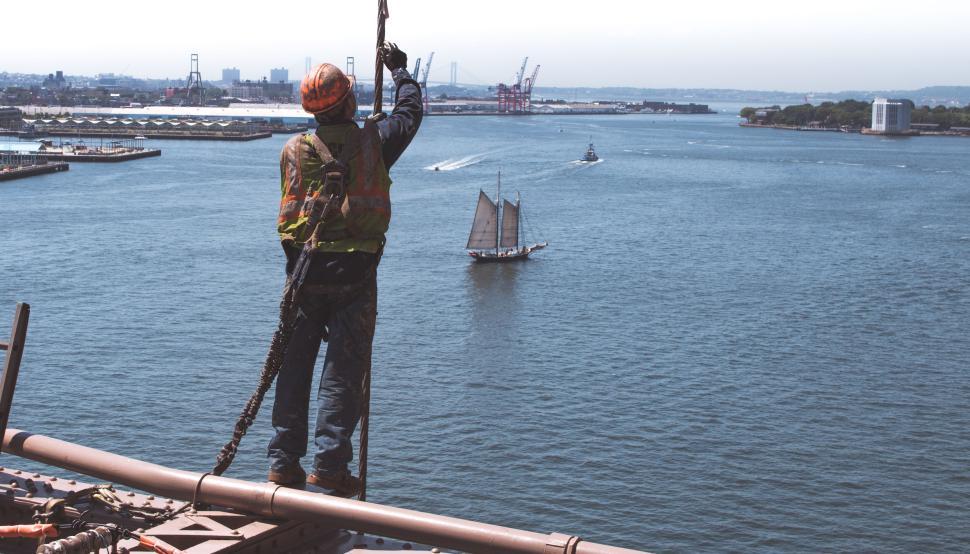 Free Image of Construction worker on high scaffold viewed by the ocean 