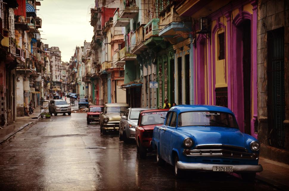 Free Image of Vintage cars parked along a colorful street in an old city 