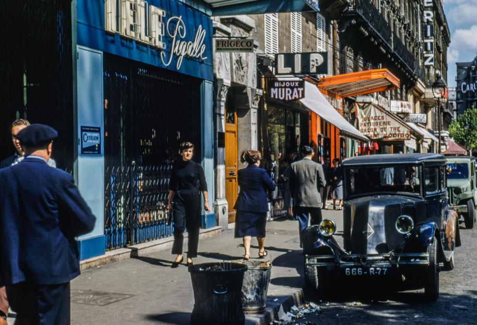 Free Image of Busy street scene showcasing urban life with shops and classic cars. 