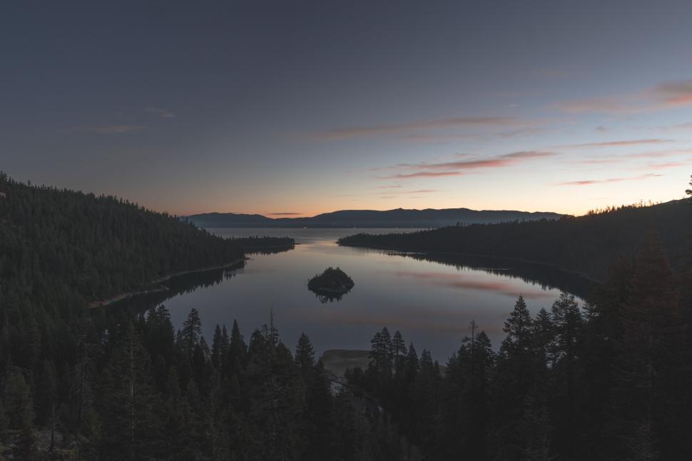 Free Image of Serene lake with small island in the center at dusk surrounded. 
