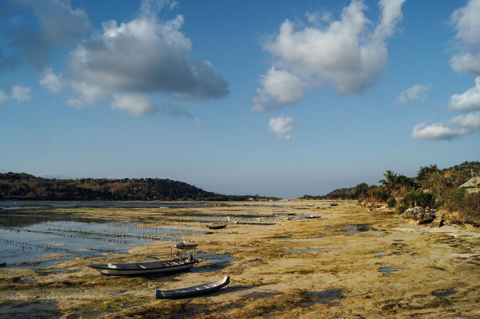 Free Image of Boats resting on shallow waters with a scenic backdrop of hills. 