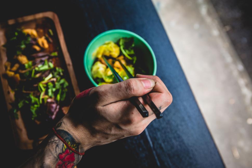 Free Image of Hand holding chopsticks above two bowls of Asian food for snack 