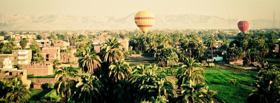Free Image of Scenic hot air balloons floating over lush green landscape at dawn 