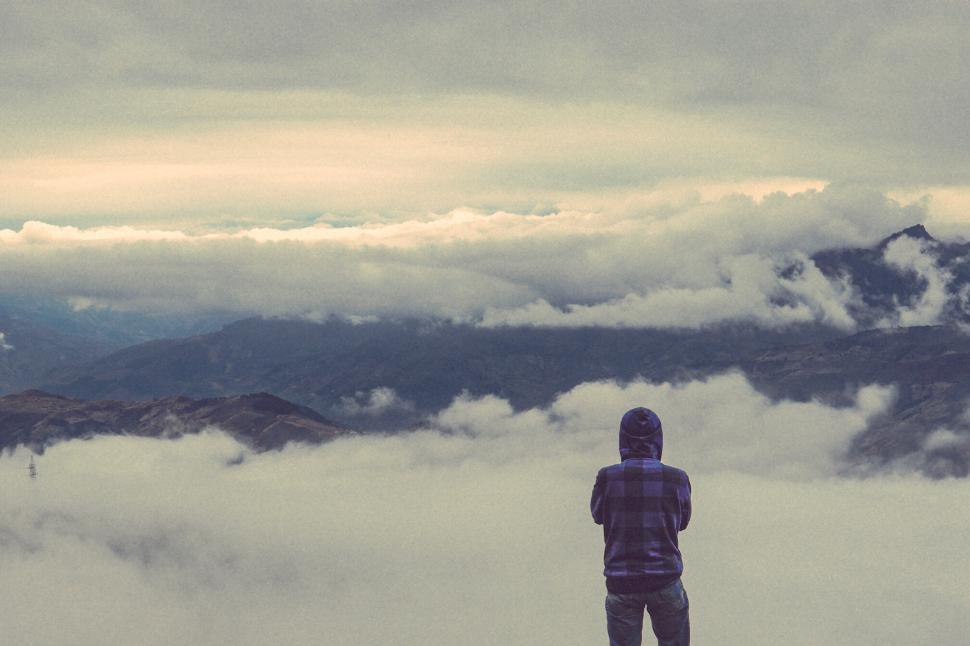 Free Image of Person standing above the clouds gazing at a panoramic mountain view. 