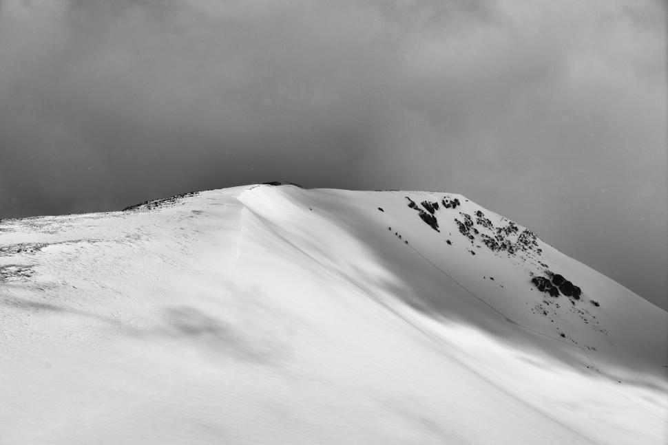 Free Image of Snowy mountain peak with dramatic shadows in black and white. 